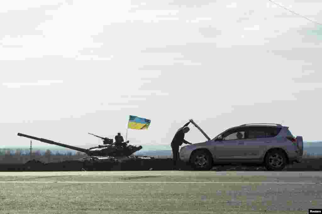 A motorist checks his car next to a Ukrainian tank position close to the border with Russia, near the city of Kharkiv. (Reuters/Dmitry Neymyrok)