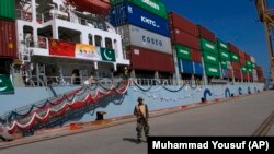 Пакистанский военный в порту Гвадар на фоне готовящегося к отплытию груженого китайского контейнеровоза 