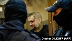 Former Russian policeman Vladimir Vorontsov stands inside a defendants' cage during a court hearing in Moscow in July 2020.