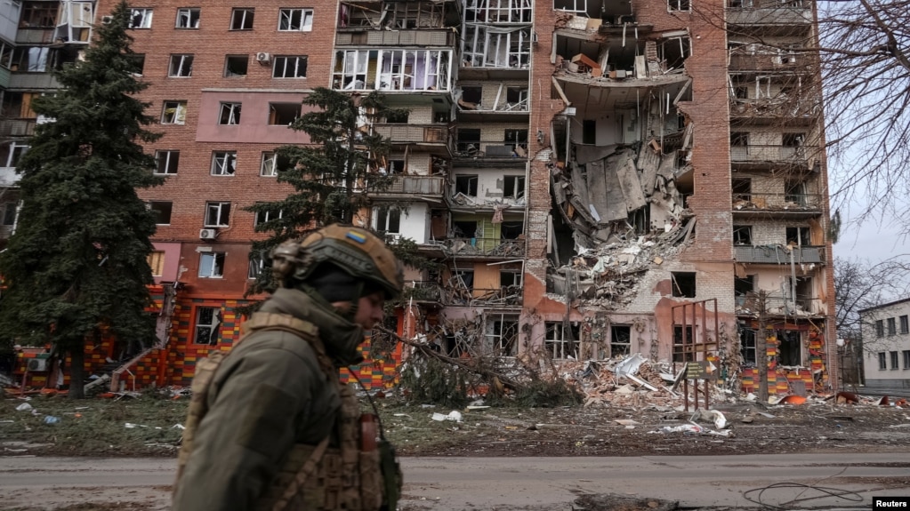 Украински военен е заснет пред разрушена от руските военни жилищна сграда в град Покровск.