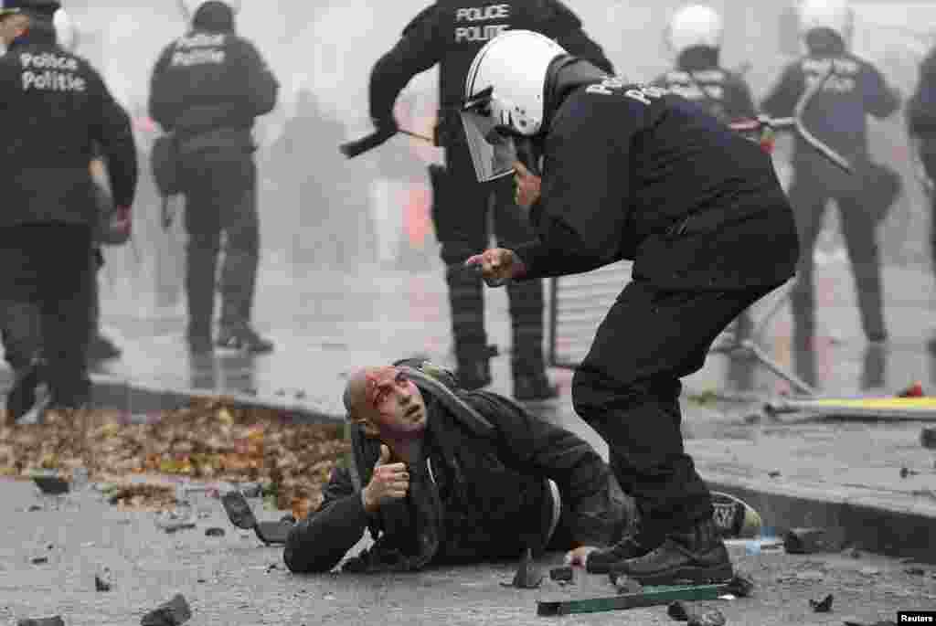 A demonstrator is restrained by riot police during clashes in central Brussels. Tens of thousands of public and private sector workers, employees, and trade union members demonstrated over austerity measures to be taken by the new Belgian government. (Reuters/Francois Lenoir)
