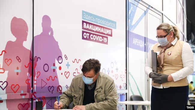 Мужчина во время заполнения информированного согласия на вакцинацию в прививочном пункте в торговом центре Арена Плаза