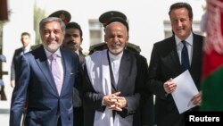 Britain's Prime Minister David Cameron walks with Afghanistan's President Ashraf Ghani (C) and Abdullah Abdullah.