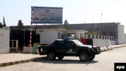 Afghan security officials stand guard outside the government guesthouse after a bomb blast in Kandahar.