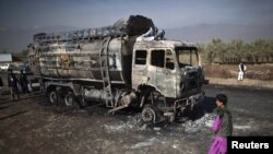 Afghanistan -- A boy walks past a burnt fuel tanker in Parwan province.