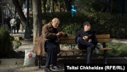 Fotoqraf Indigo Fleur bu səhnəni Tbilisidəki Qızılgül Parkında çəkib. Yaşlı kişi alma payını yanında oturan gənclə bölüşür.