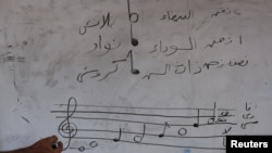 Osama Jahjouh ney-fuvolatanár kottázik a táblára a Gázai Főiskolán, ahol az Edward Said Nemzeti Zenei Konzervatórium tanárai tartanak órákat Gázavárosban 2025. augusztus 9-én.