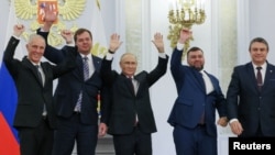 Russian President Vladimir Putin (center) cheers alongside Denis Pushilin, Leonid Pasechnik, Vladimir Saldo, and Yevgeny Balitsky, the respective Russian-installed administrators in Ukraine's Donetsk, Luhansk, Kherson, and Zaporizhzhya regions, at the September 30 signing ceremony.