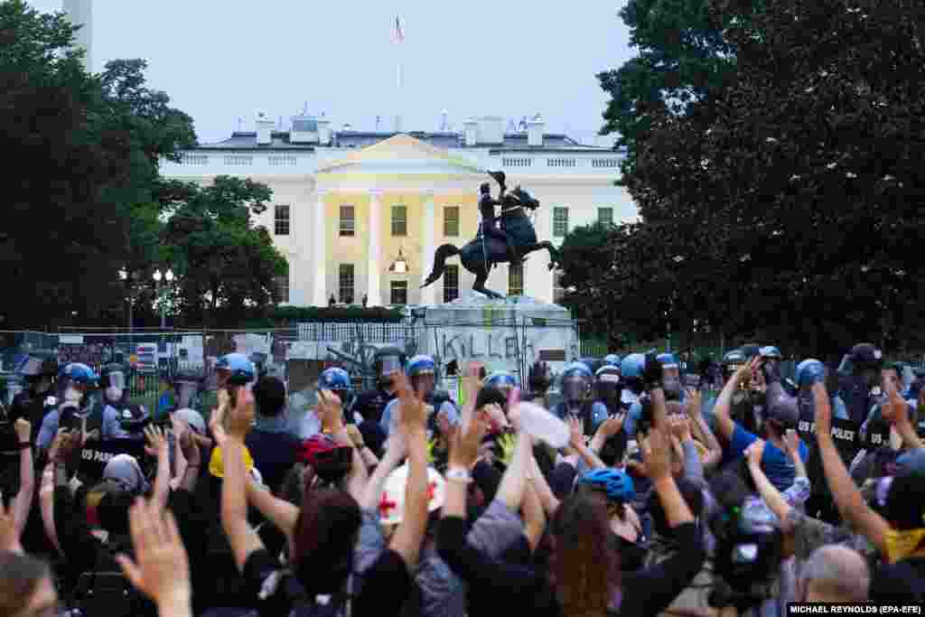 Протестувальники підняли руки вгору перед поліцією, яка використовувала хімічні речовини, щоб зупинити протестувальників, які намагалися знести пам&rsquo;ятник у парку Лафаєт. Вашингтон, округ Колумбія, США