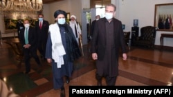 Pakistani Foreign Minister Shah Mehmood Qureshi (right) walks with Taliban co-founder Mullah Abdul Ghani Baradar upon his arrival in Islamabad with the delegation for talks on December 16, 2020.