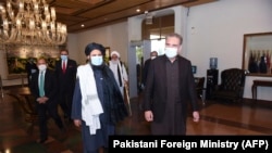 Pakistani Foreign Minister Shah Mehmood Qureshi (right) walks alongside Taliban co-founder Mullah Abdul Ghani Baradar upon the delegation's arrival for talks in Islamabad on December 16.