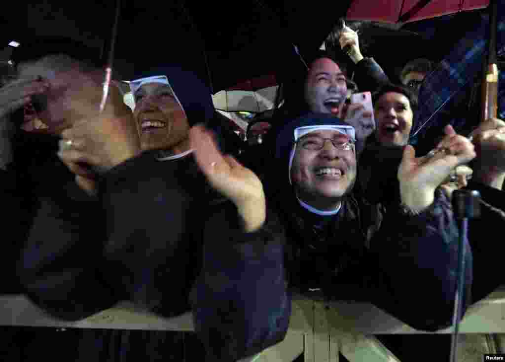 People cheer as white smoke rises from the chimney above the Sistine Chapel, indicating a new pope has been elected at the Vatican.