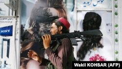Боец «Талибана» с ружьем американского производства проходит мимо салон красоты с изображениями женщин, закрашенных аэрозольной краской в Шар-э-Нау
