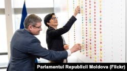 Comisara europeană pentru Extindere, Marta Kos, și spicherul moldovean, Igor Grosu, într-o fotografie difuzată de parlamentul moldovean, numărând reformele pe o tablă, la Bruxelles, pe 17 martie 2026 