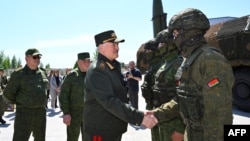 Președintele din Belarus, Al. Lukașenko (centru), salută participanții la manevrele militare comune cu Rusia, pe 21 mai 2026.  
