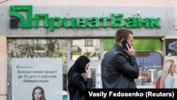 People walk past a branch of PrivatBank, the country's biggest lender, in Kyiv.