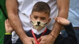 ROMANIA -- A father with his son wearing a protective face mask wait in front of a school in Bucharest September 14, 2020, where classes started again after the summer break. 