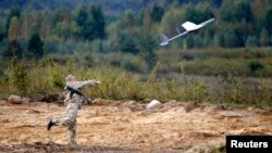 Беларус аскари Минск жанубидаги Осипович шаҳри яқинида дрон учираётган пайт, 2013 йил 25 сентябрь.