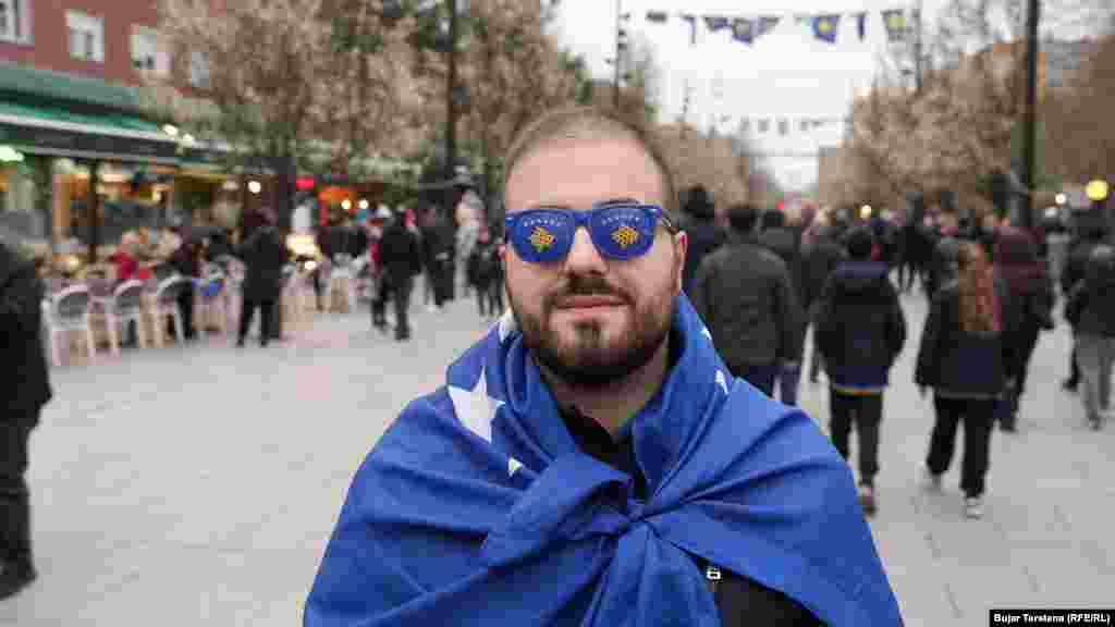 Një burrë i mbështjellë me flamurin e Kosovës shihet në sheshin e Prishtinës, disa orë para ndeshjes vendimtare mes Kosovës dhe Turqisë për një vend në Kupën e Botës 2026, të martën në Stadiumin "Fadil Vokrri".