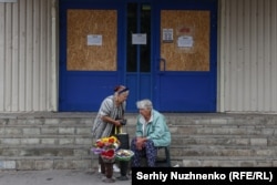 Жінки продають квіти та продукти з власного господарства біля зачиненого супермаркету в місті Покровську Донецької області. 3 вересня 2024 року