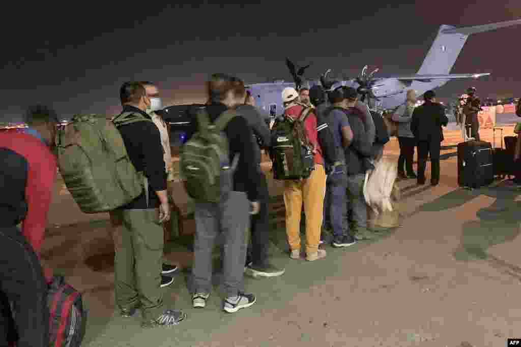 French and Afghan nationals line up to board a French military transport plane at Kabul airport.