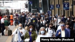 Védőmaszkot viselő emberek sétálnak a King’s Cross pályaudvar egyik peronján a koronavírus-járvány idején Londonban 2021. július 12-én