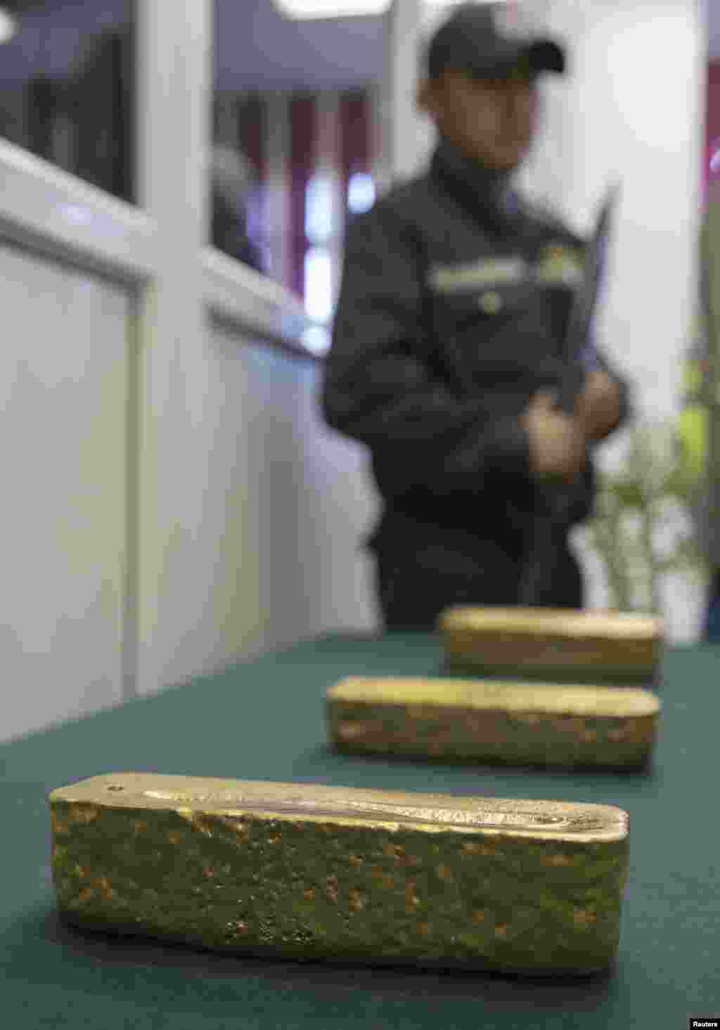 &nbsp;An armed guard stands by as gold alloy bars are put on display.