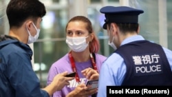 Белорусская спортсменка Кристина Тимановская беседует с полицейским в международном аэропорту Ханеда в Токио, 1 августа 2021 года