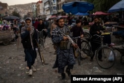 Taliban fighters patrol a market in Kabul on September 24.