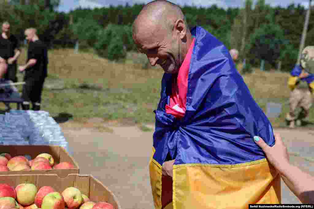 Колишній військовополонений дивиться, усміхаючись, на яблука, яких в полоні не було