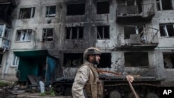 Український військовий проходить повз пошкоджений обстрілами житловий будинок у Часовому Яру, 9 травня 2023 року