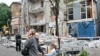 Люди проходять повз багатоповерховий житловий будинок, пошкоджений внаслідок удару безпілотника в Києві 25 травня 2025 року