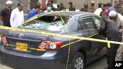 Police and investigators gather around a car used by the attackers in Karachi on June 29.