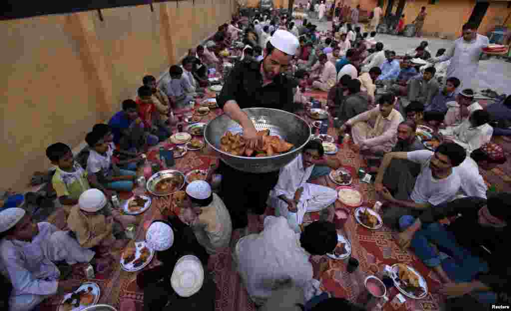 A man distributes samosas, a traditional delicacy consumed during the holy fasting month of Ramadan, to men before breaking their fast in Rawalpindi, Pakistan. (Reuters/Faisal Mahmood)