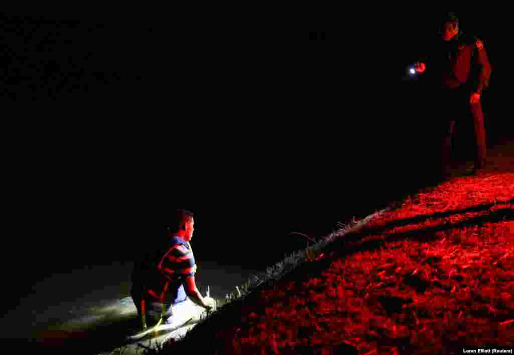 An immigrant who jumped into a canal in an effort to escape capture after illegally crossing the Mexican-U.S. border gives up and turns himself in to a border patrol agent in the Rio Grande Valley sector, near McAllen, Texas. (Reuters/Loren Elliott)