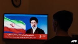 مردی در ۱۲ مارچ ۲۰۲۶ بیانیهٔ تلویزیونی منتسب به مجتبی خامنه‌ای، رهبر جدید ایران را تماشا می‌کند.