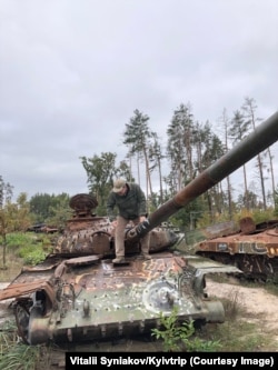 A war tourist explores a tank in the Kyiv region