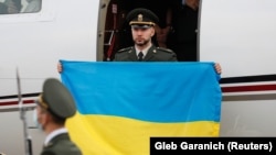 Ukrainian National Guard serviceman Vitaliy Markiv holds a Ukrainian national flag as he arrives at an airport in Kyiv on November 4.