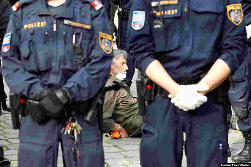 An elderly man wearing a face mask is arrested by Austrian police in Vienna during a demonstration against the anti-coronavirus measures taken by the government.