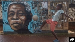 Dijete šutira loptu ispred murala Nelsona Mandele u Sowetu, u Južnoj Africi, 27. aprila 2024. na praznik nazvan Dan slobode kojim se obilježava datum od prvih ključnih demokratskih izbora 1994. koji su najavili službeni kraj rasne segregacije i ugnjetavanja.