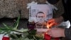 Людина запалює свічку біля портрета російського опозиціонера Олексія Навального біля пам’ятника жертвам політичних репресій, Санкт-Петербург, Росія, 16 лютого 2024 року