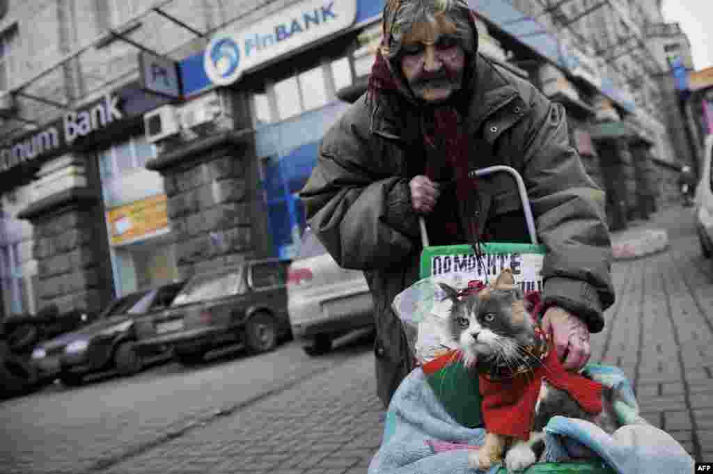 An elderly woman and her cat on a street in central Kyiv on February 24. (AFP/Louisa Gouliamaki)