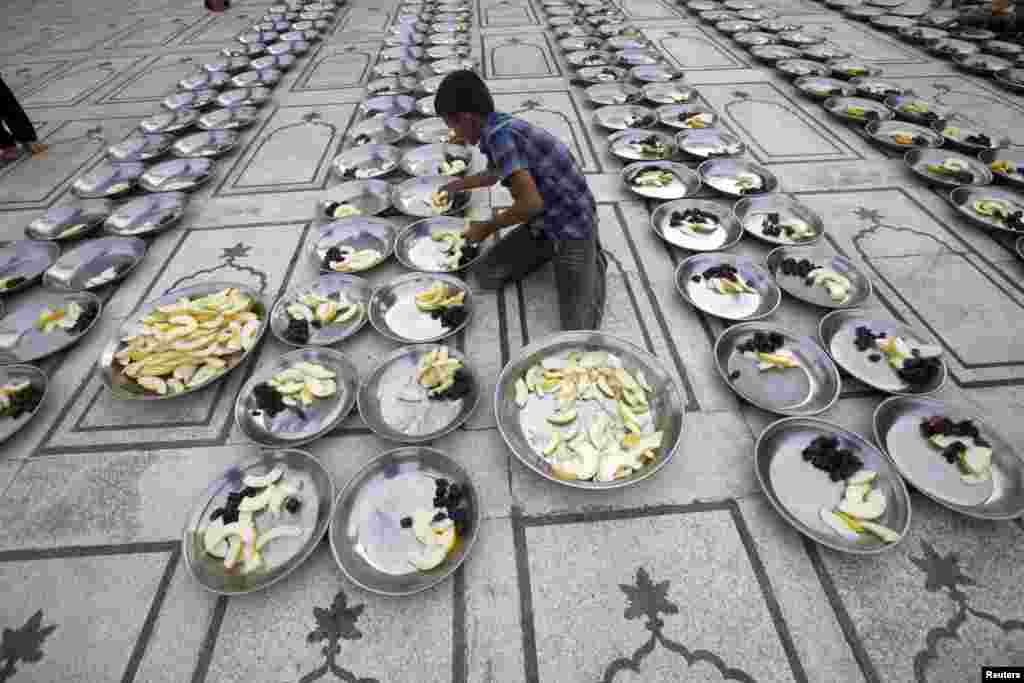 A volunteer prepares plates for the breaking of the fast, known as iftar, during the holy month of Ramadan at a mosque in Karachi, Pakistan. (Reuters/Athar Hussain)