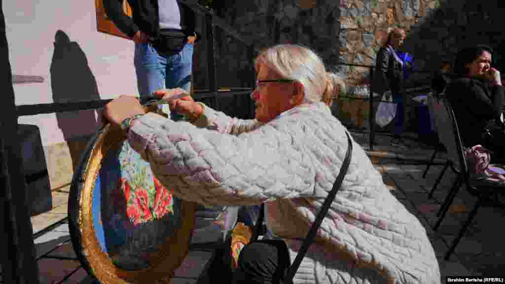 Një grua ekspozon një kornizë me një pikturë të qëndisur me dorë në panairin e produkteve tradicionale në Janjevë. &nbsp;