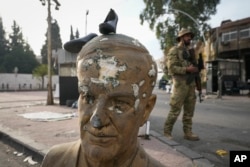  Боец от опозицията до строшен бюст на починалия сирийски президент Хафез Асад с чифт обувки върху главата му, Дамаск, Сирия, 11 декември 2024 година 