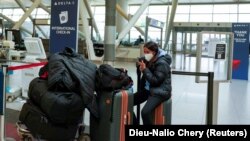 Патничка седи со својот багаж на меѓународниот аеродром Џон Кенеди, откако авиокомпаниите објавија дека се откажани бројни летови поради ширењето на варијантата омикрон