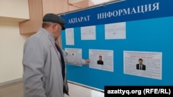 Мужчина у стенда с информацией о кандидатах на должность сельского акима. Западно-Казахстанская область, 25 ноября 2021 года