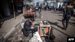 Палестинский мужчина ремонтирует обувь на улице Рафаха, 19 февраля 2024 года.