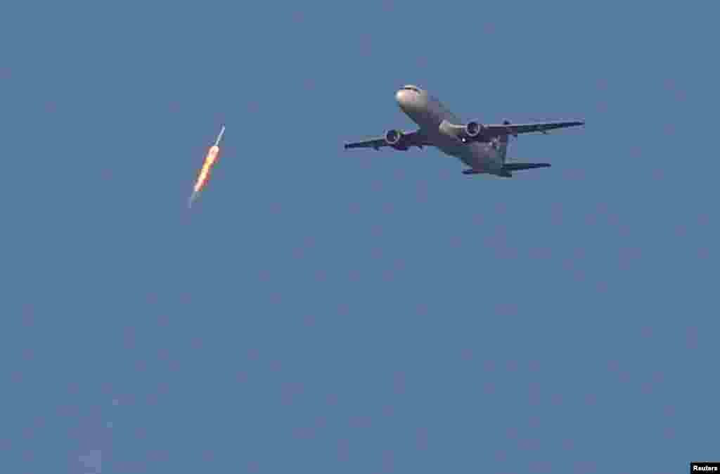 A recycled SpaceX Falcon 9 rocket soars toward space above a Virgin Airlines passenger jet, which had just departed Orlando International Airport in Florida on March 30. (Reuters/Gregg Newton)