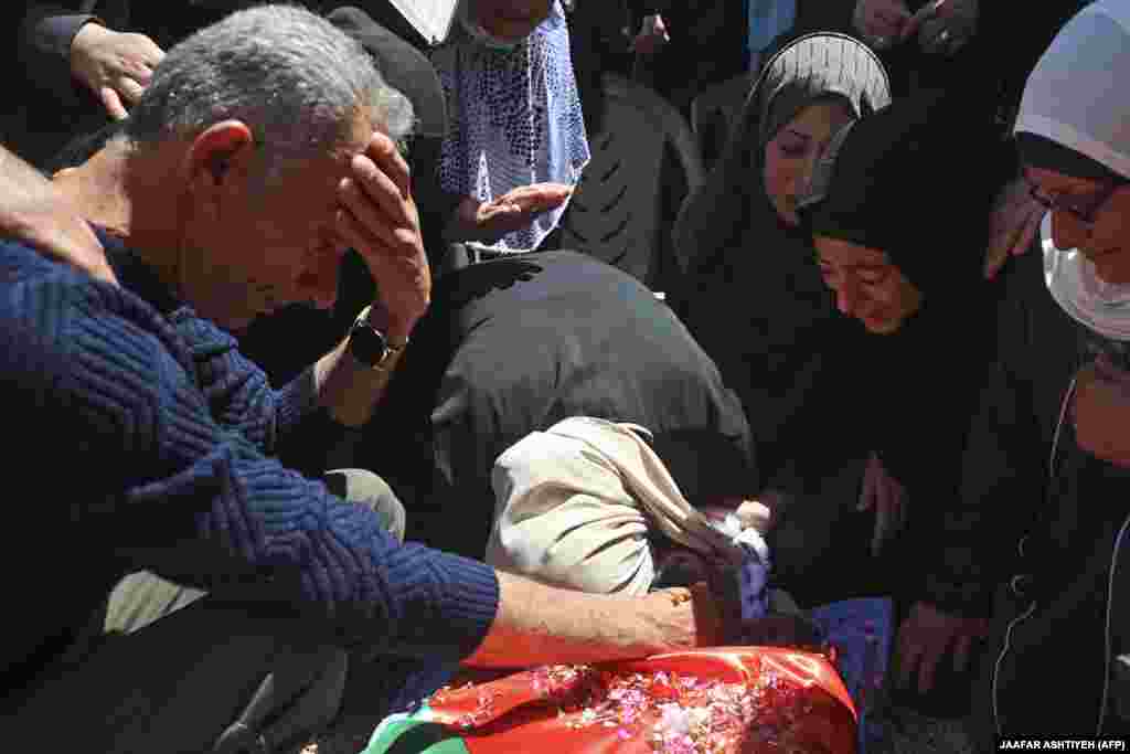 Të afërmit vajtojnë afër trupit të pajetë të palestinezit Yaseen Hamad, i cili është vrarë nga të shtënat izraelite në trazirat në Bregun Perëndimor, gjatë funeralit të tij në fshatin Seida, afër Tulkaremit, më 16 maj 2021. Katër palestinezë janë vrarë nga të shtënat izraelite në Bregun Perëndimor më 14 maj, përfshirë një që ishte përpjekur ta therte një ushtar, teksa përleshjet kanë lënë më shumë se 100 njerëz të plagosur në territorin e okupuar.